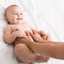 Colics prevention. Masseur massaging tummy of newborn baby, healthcare and babycare, copy space